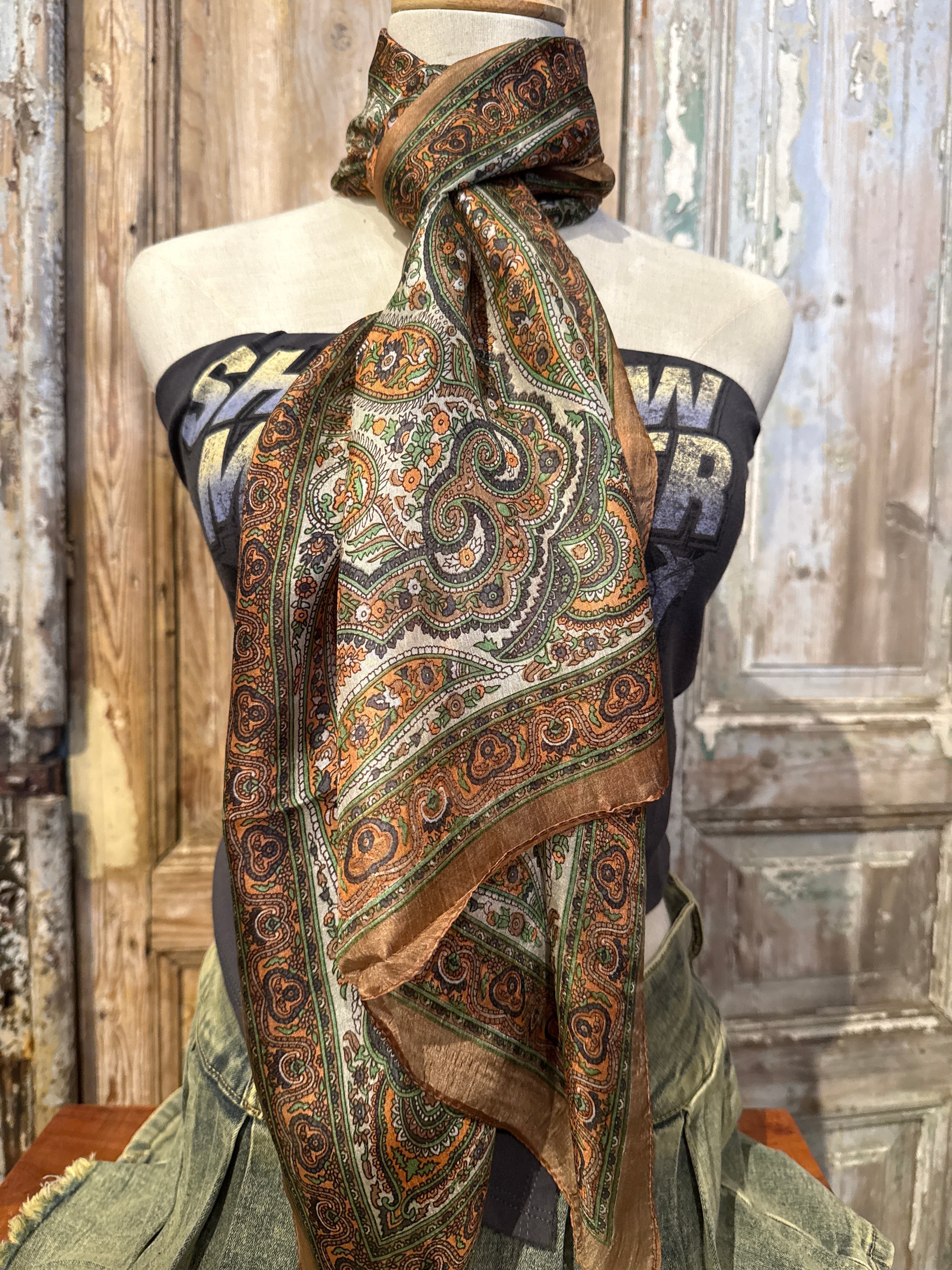 Trestles Clothing Company silk boho scarf featuring a vibrant paisley print in earthy brown, green, and orange tones.